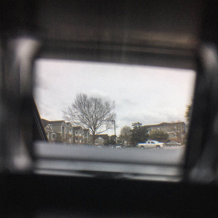 an album cover of the inside of a car windoe looking out, a neiborhood and tree is shown