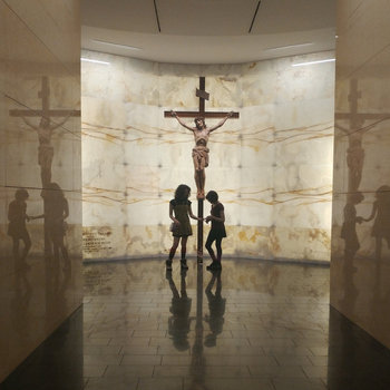 an album cover of two girls touching hands, the light is framed to make them look like siloettes, there is a large cross between them