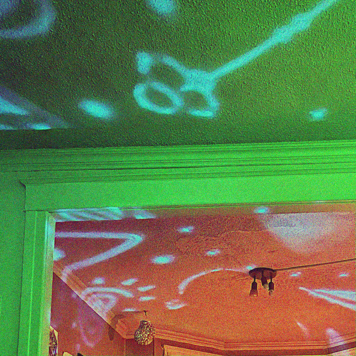 a grainy, cropped photo of squiggly lasers projected on a DIY venue ceiling, one room green, one room red