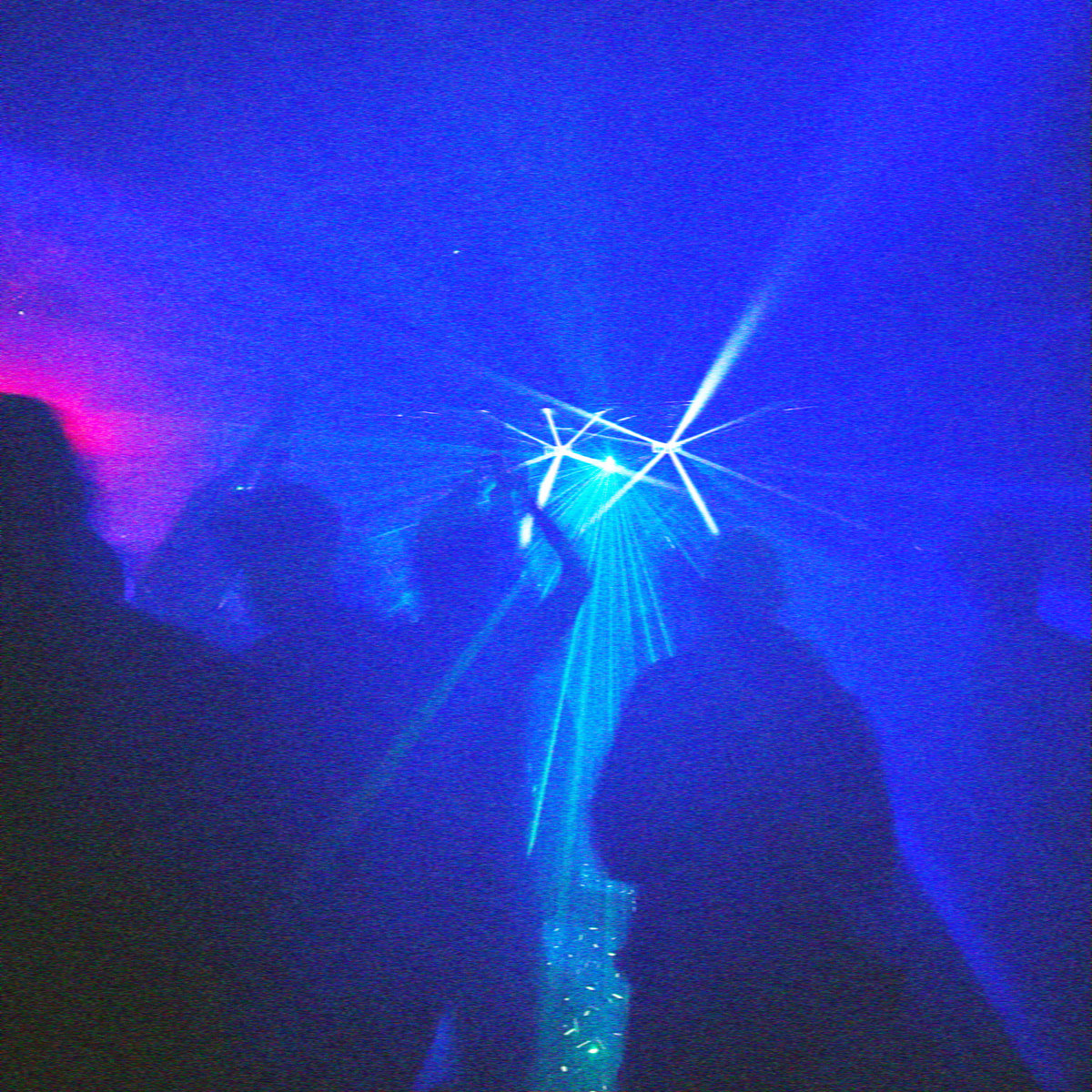 Silhouettes of bodies dance before a cascade of lasers in a blue dance floor fog